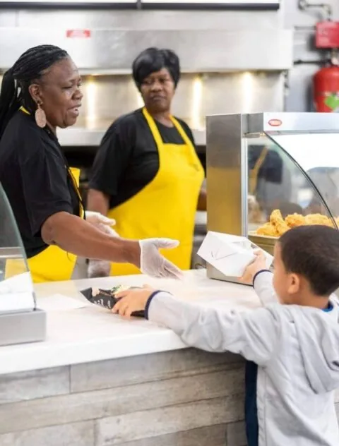 A Creole Fried Chicken team member serving a customer at the counter